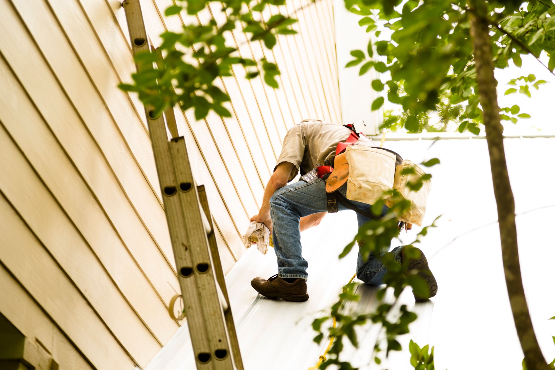 Repairman, roofer repairs metal roof. Home. Ladder, tools. Construction worker.